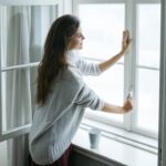 Woman is opening window to look at beautiful snowy landscape outside