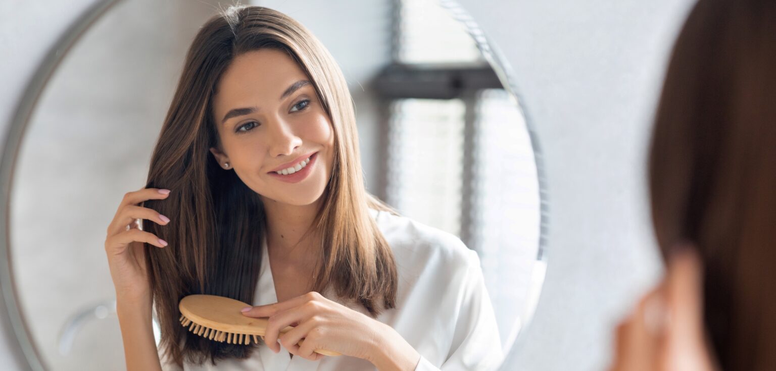 Woman brushing her long healthy hair due to high-quality hair vitamins and supplements can that promote hair growth