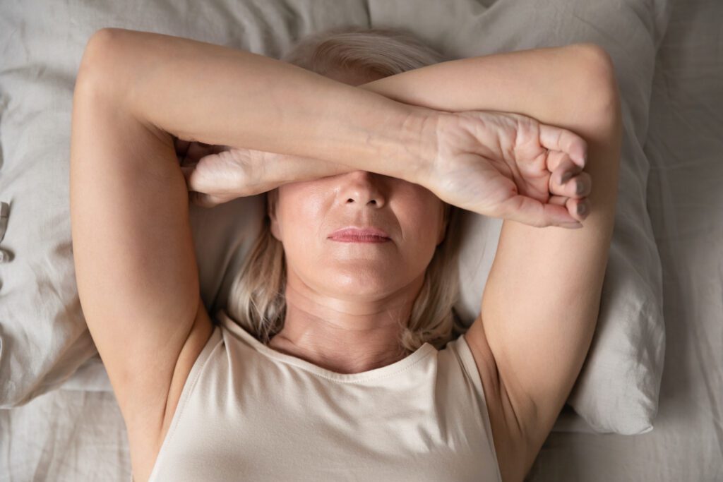 Sleepless mature woman suffering from insomnia, lying in bed and trying to sleep.