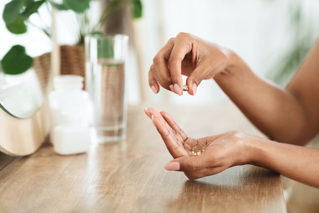 Woman Taking Beauty Supplements For Glowing Skin, Holding Omega-3 Fish Oil Capsules In Hands